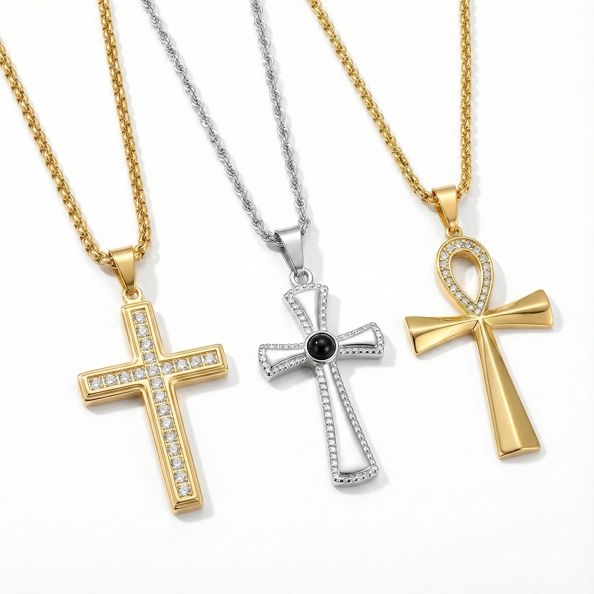 Trio of women's cross necklaces on twisted rope chains: Classic gold pave cross, silver artistic cross with black center stone, and crystal-studded gold Ankh pendant.