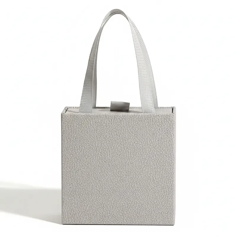 Minimalist grey textured jewelry gift box with ribbon handles for Crystia cross necklaces.