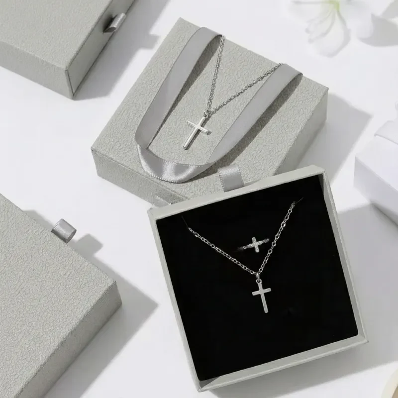 crystia premium case Silver cross necklace and matching ring displayed inside a premium grey drawer-style jewelry box with black velvet lining.