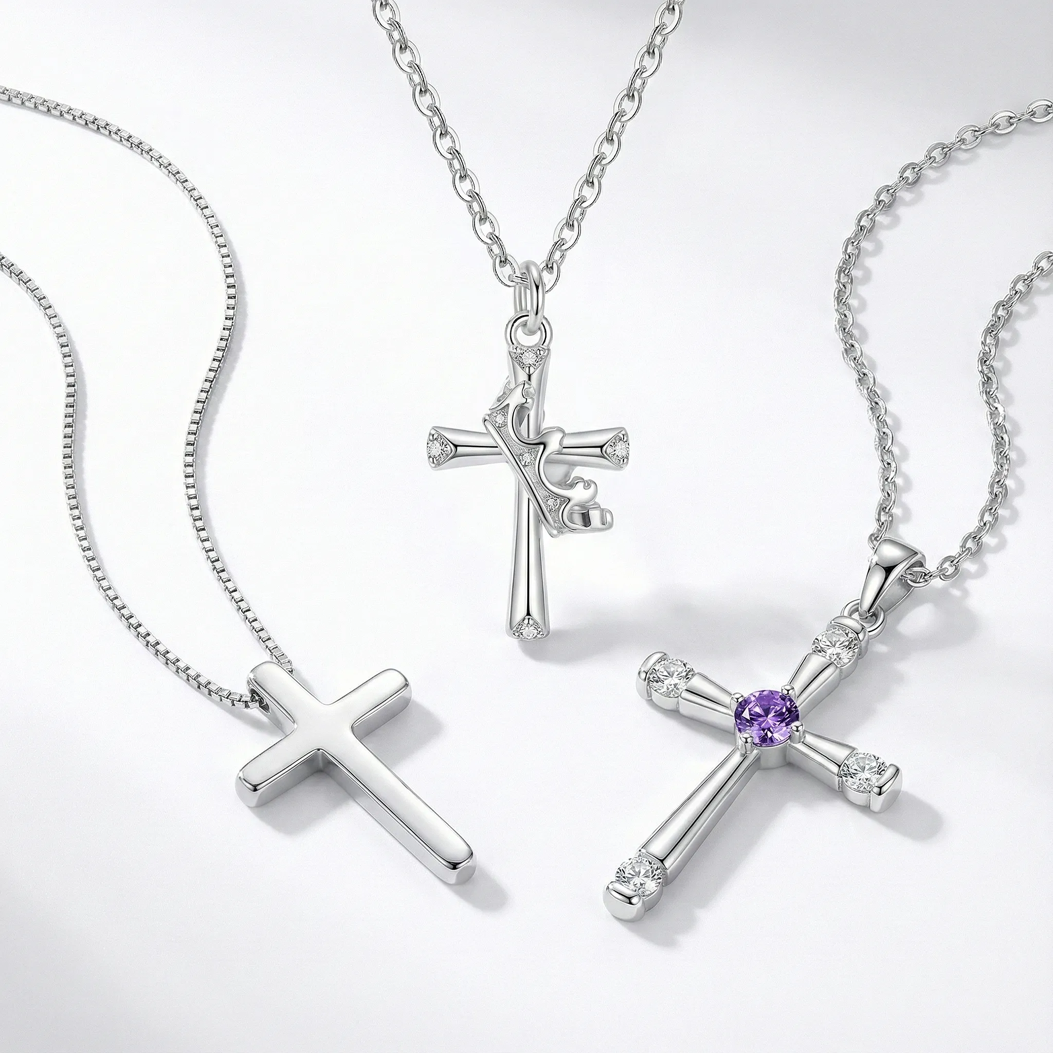 Trio of silver women's cross necklaces: minimalist polished cross, artistic ribbon design, and crystal cross with purple amethyst center stone.