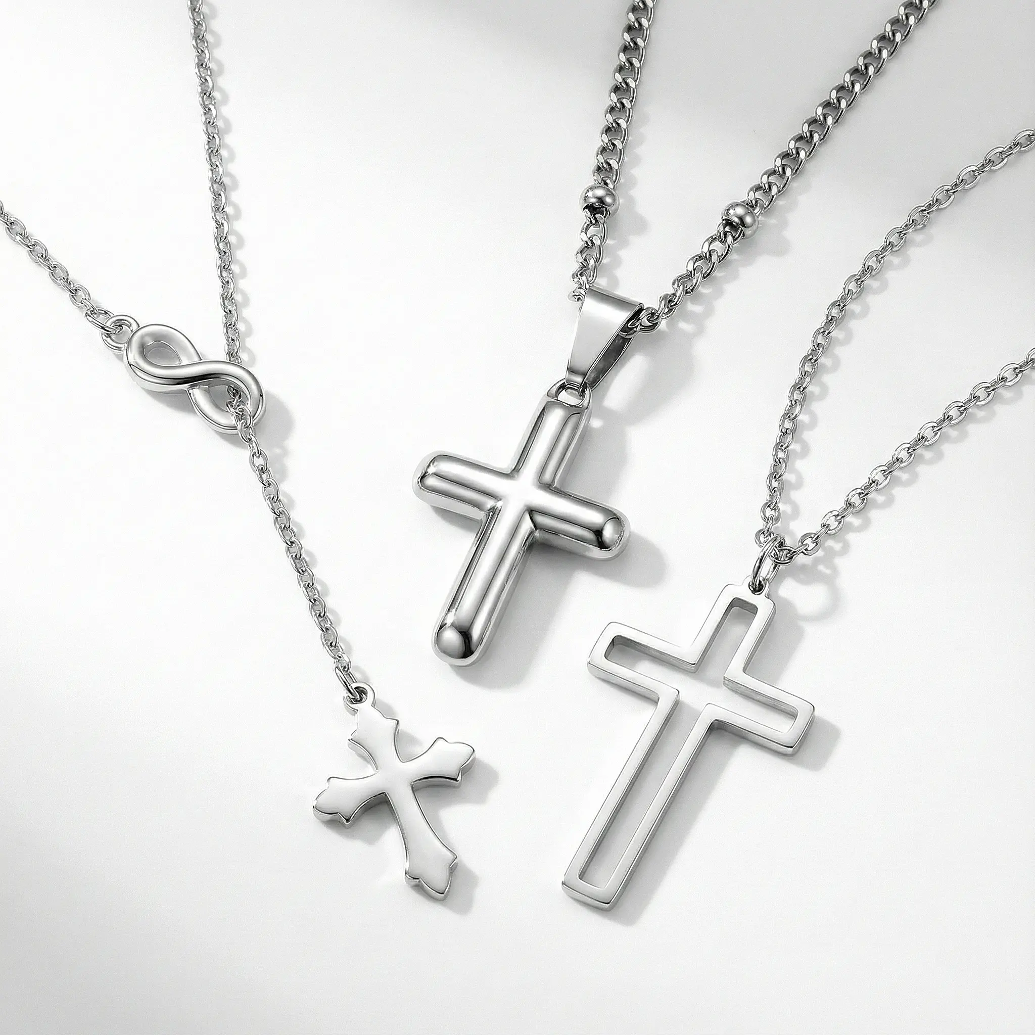 Modern silver cross necklaces: Infinity lariat Y-necklace, smooth rounded puff cross, and geometric cutout outline cross.