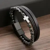 Men's stone bead cross bracelet coiled on a wooden table, polished steel cross centered