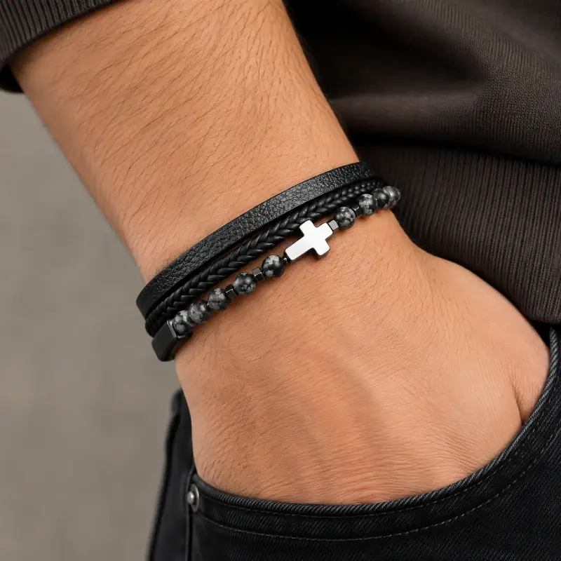catholic cross bracelet leather kedron Man wearing a multi-strand Catholic cross leather bracelet, polished steel cross visible on the wrist
