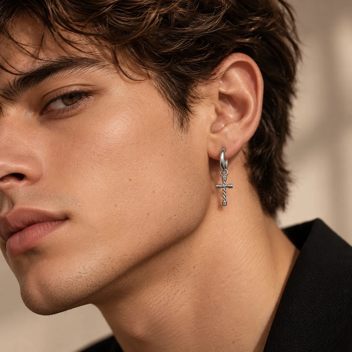 Young man in a black blazer wearing a rope cross hoop earring, three-quarter profile