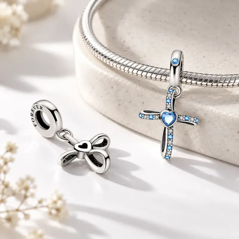 blue cross charm maris Blue stone cross dangle beside a silver snake bracelet, showing the openwork reverse