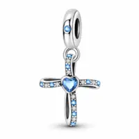 Sterling silver cross charm with blue heart stone and alternating pavé arms, white background