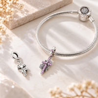 Silver snake bracelet carrying a floral cross dangle, with the pierced reverse shown beside it
