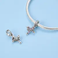 Crown and cross charm shown front and reverse beside a silver snake chain bracelet