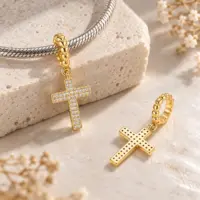 Diamond-look gold cross on a silver snake bracelet, second charm showing its pierced back