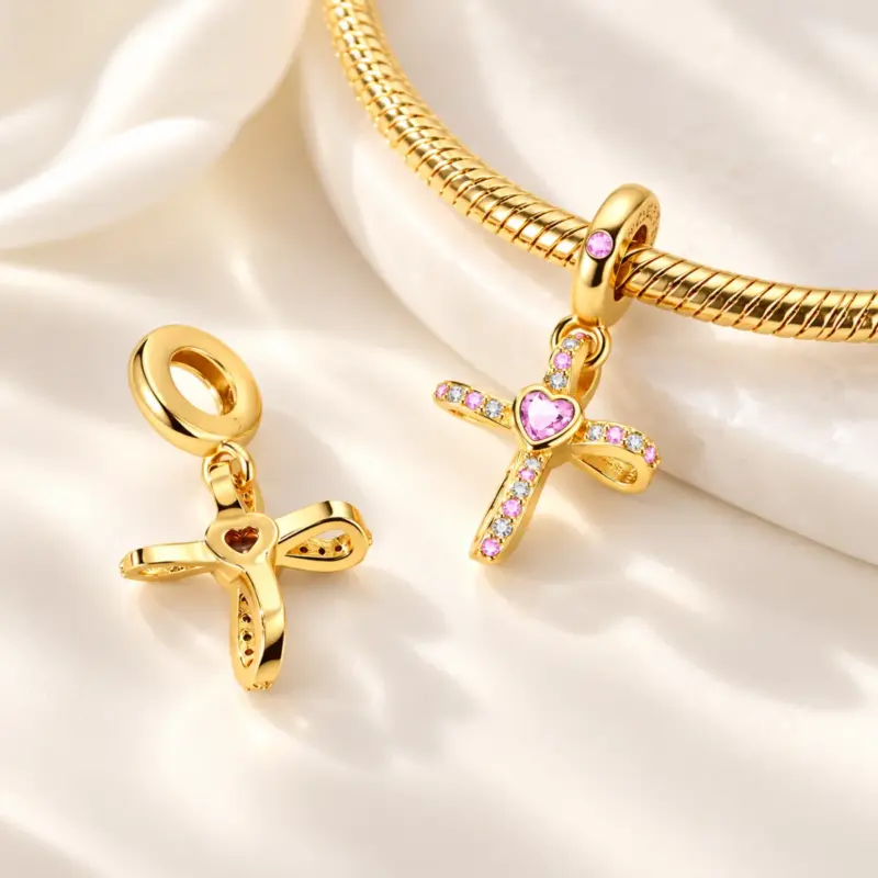 women's gold cross charm Women's gold cross charm on gold snake chain bracelet beside a charm showing its heart-window back