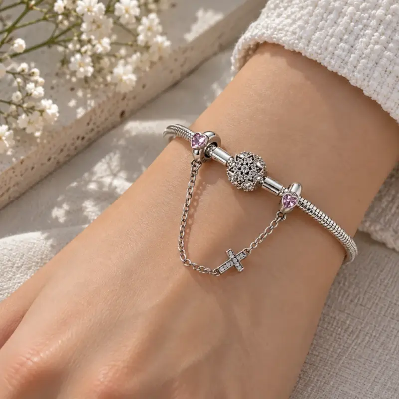 bracelet safety chain Charm bracelet safety chain draped on a wrist beside a pavé bead, knit sleeve above
