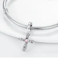 Pink heart cross pendant charm hanging from a silver snake chain bracelet