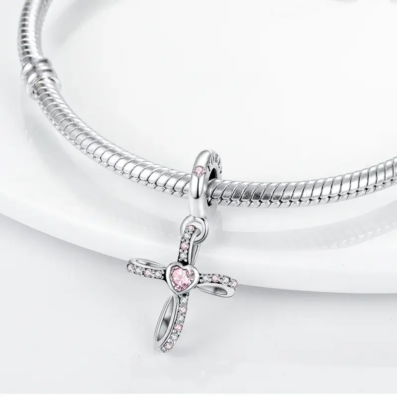 Pink heart cross pendant charm Pink heart cross pendant charm hanging from a silver snake chain bracelet