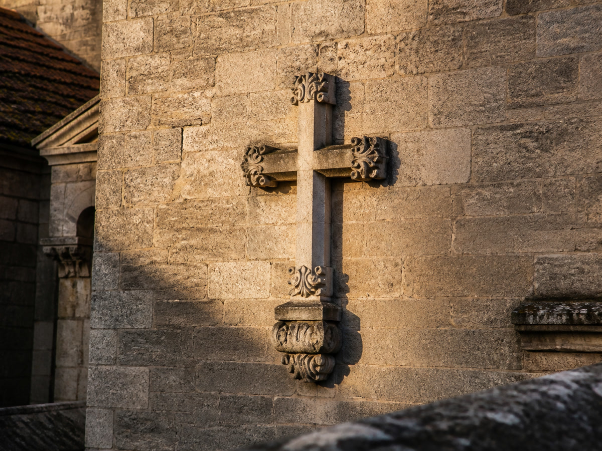 Antique stone Latin cross on the wall of an old European church