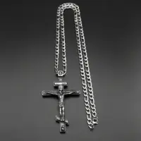 Full steel crucifix necklace laid flat with figaro chain and lobster clasp visible