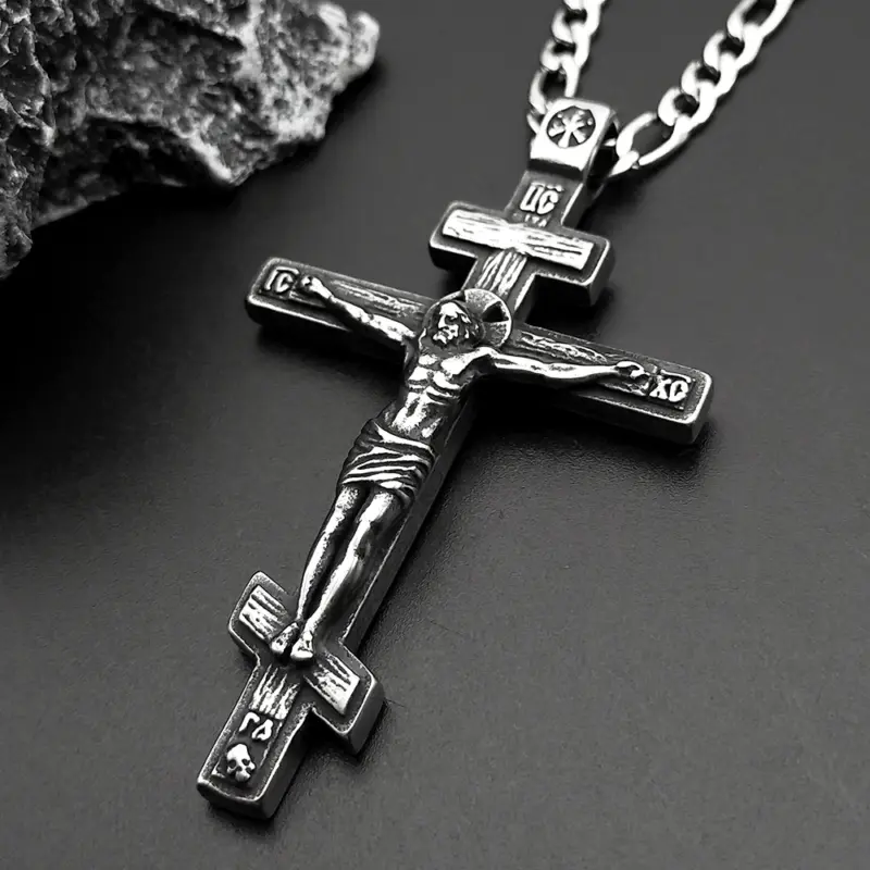 three-bar-cross-pendant-detail.webp Three-bar Orthodox cross pendant angled on dark stone, corpus and skull in relief