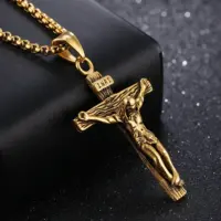 18k gold-plated crucifix necklace resting on a black block against a dark background