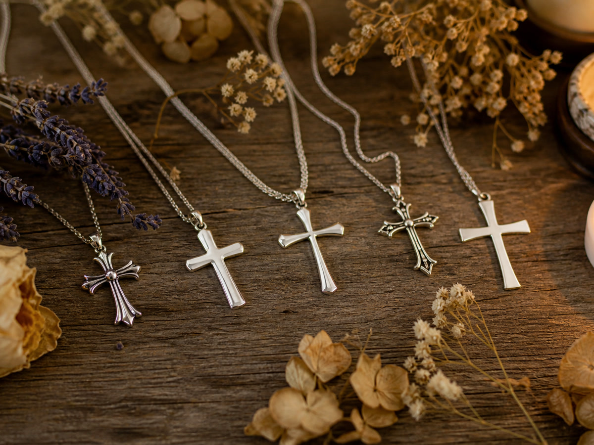 An arrangement of sterling silver cross necklaces on a rustic wooden surface with candlelight, representing the variety of cross styles and their spiritual significance.
