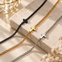 three cross link necklaces side by side in black, gold and silver finishes on stone