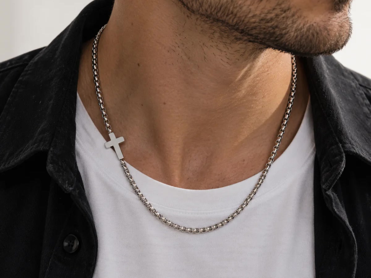 Stainless steel cross chain worn daily, a metal that resists sweat and water without staining the skin.